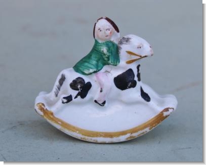 SMALL FIGURE OF A CHILD RIDING A ROCKING HORSE.