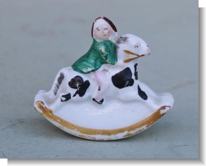 SMALL FIGURE OF A CHILD RIDING A ROCKING HORSE.